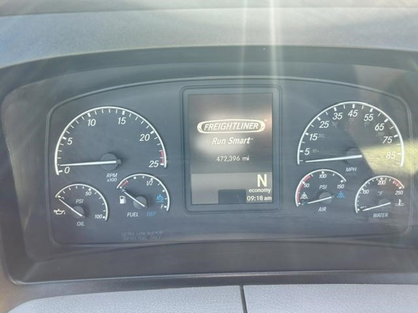 Dashboard cluster of a Freightliner Cascadia 126 showing gauges and a central screen with 'FREIGHTLINER Run Smart' and mileage, visible RPM, speed, fuel, oil, and water indicators.