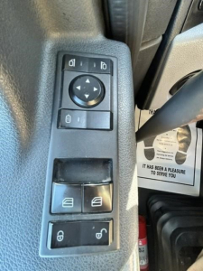 Dashboard switch panel in Freightliner Cascadia cabin showing power window controls and mirror adjustment pad.