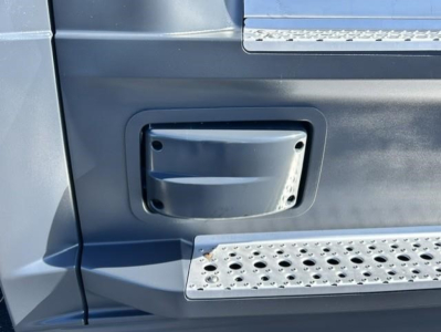 Freightliner Cascadia 126 truck door area showing a rectangular step access panel and metal diamond-plate tread with riveted edges.