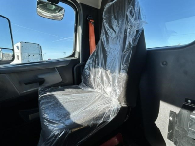 Truck cab interior showing driver seat with plastic cover and seat belt, window and dash area visible.