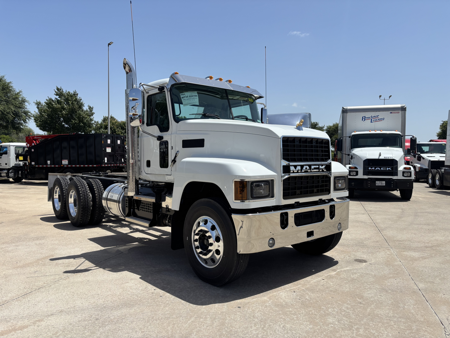 Mack PI64 dump truck in a parking lot showing front and left side profile with chrome bumper and dual rear axles.