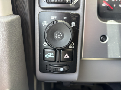Dashboard controls of a Mack Pi64 showing headlight switch dial and emergency/power controls visible.