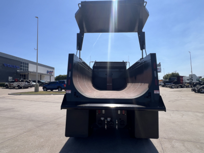 Dump truck dump bed raised showing interior with smooth metal surface and hydraulic arms.