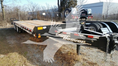 Eager Beaver flatbed trailer showing brand graphics and hydraulic hitch, with long wood deck and dual axles.