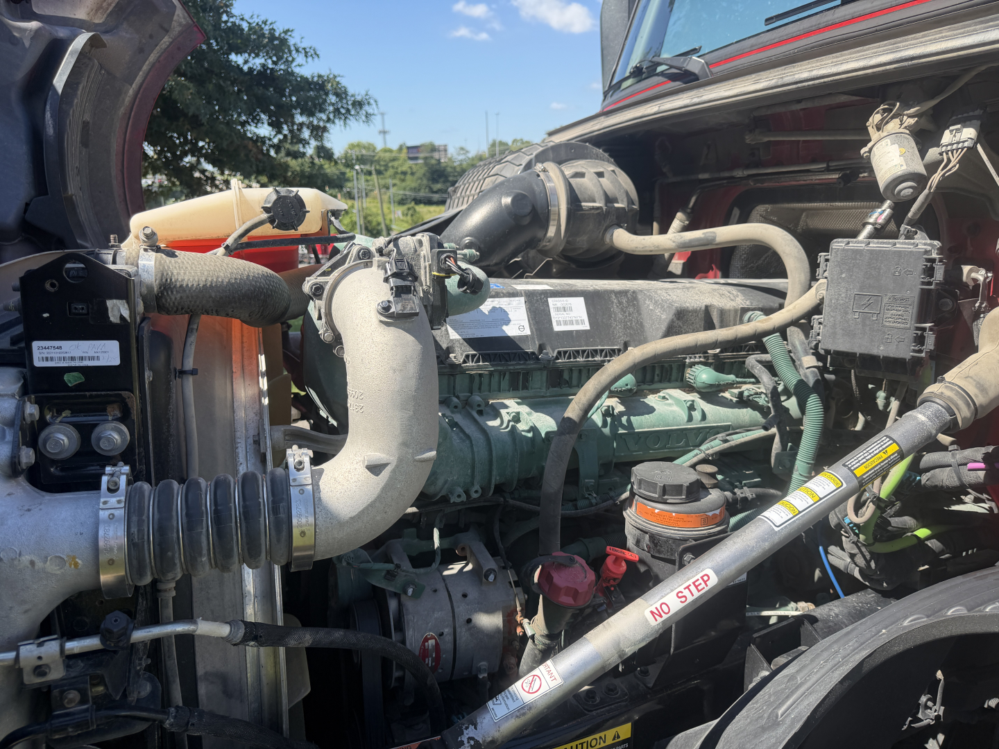 Volvo VNL64T760 engine bay showing diesel engine with coolant reservoir, hoses, and wiring harnesses visible under open hood.