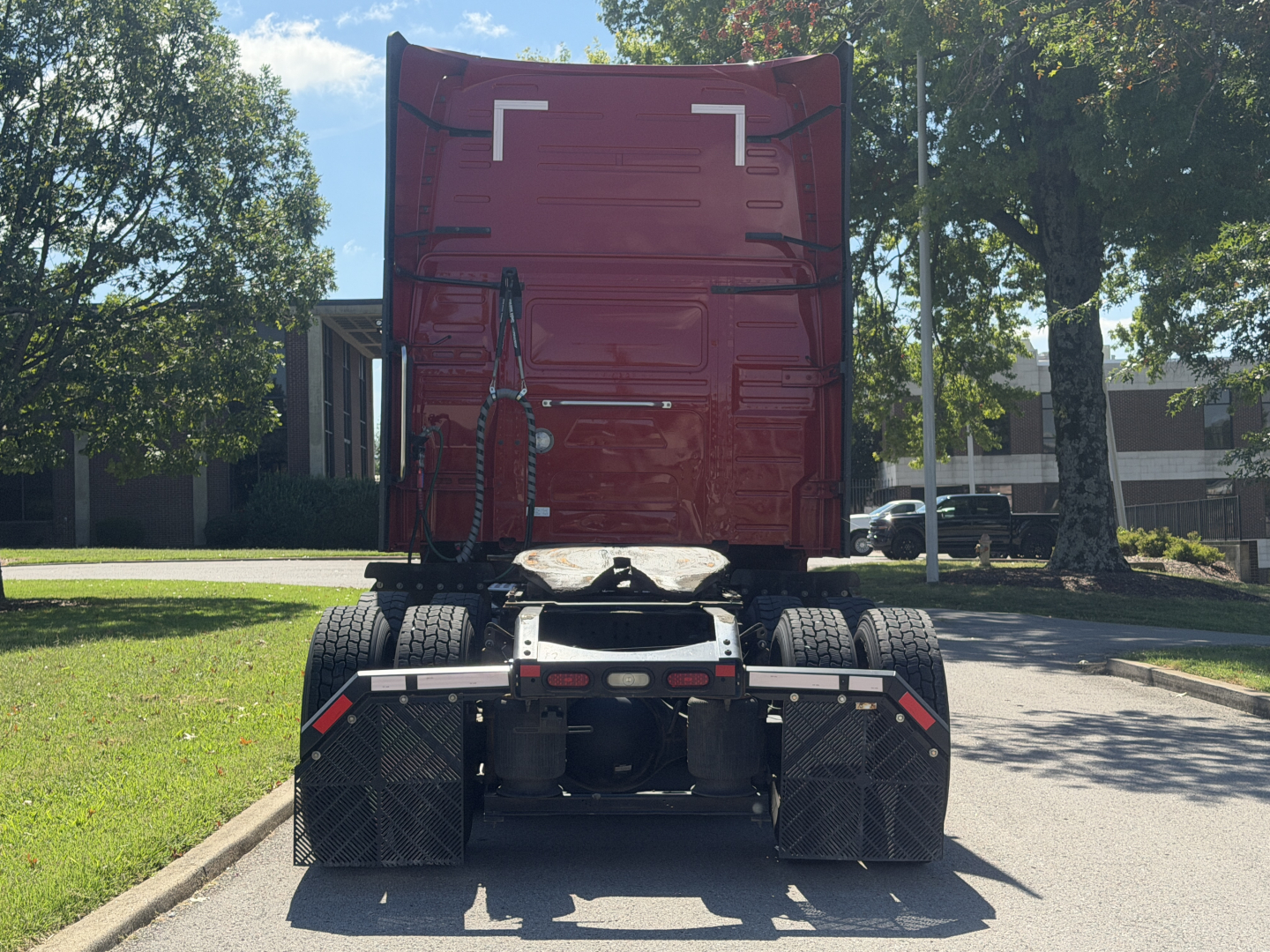 Volvo VNL64T760 tractor rear view showing bumper, dual rear axles, and red sleeper cab in a parking lot.