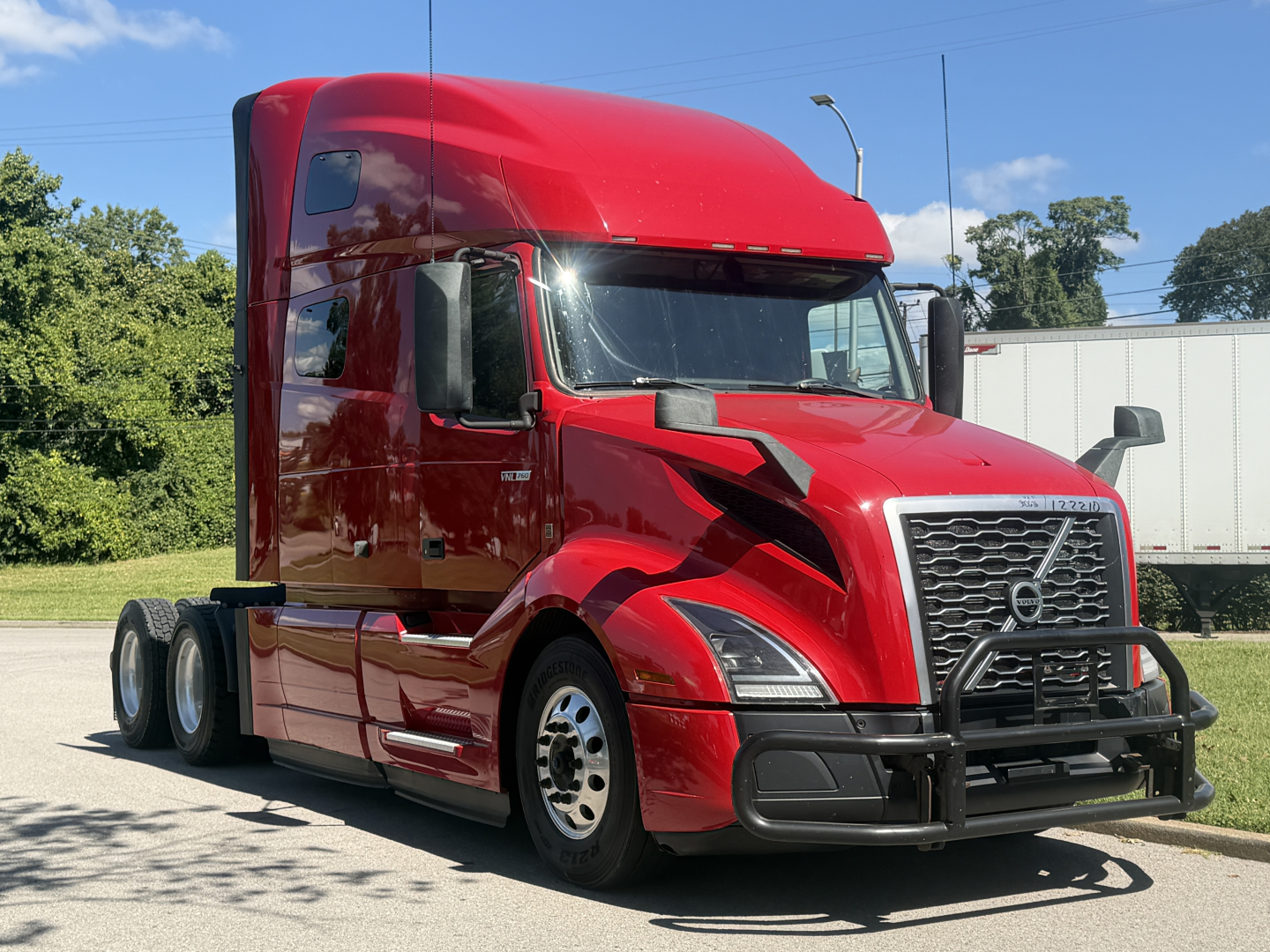 Volvo VNL64T760 truck in red, front-right view, diesel sleeper cab with bumper guard and grille grille, highway background.