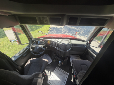 Truck cab interior showing steering wheel, dashboard, and front seats of a 2022 Volvo VNL64T760 sleeper, with driver’s seat on left and passenger bench.