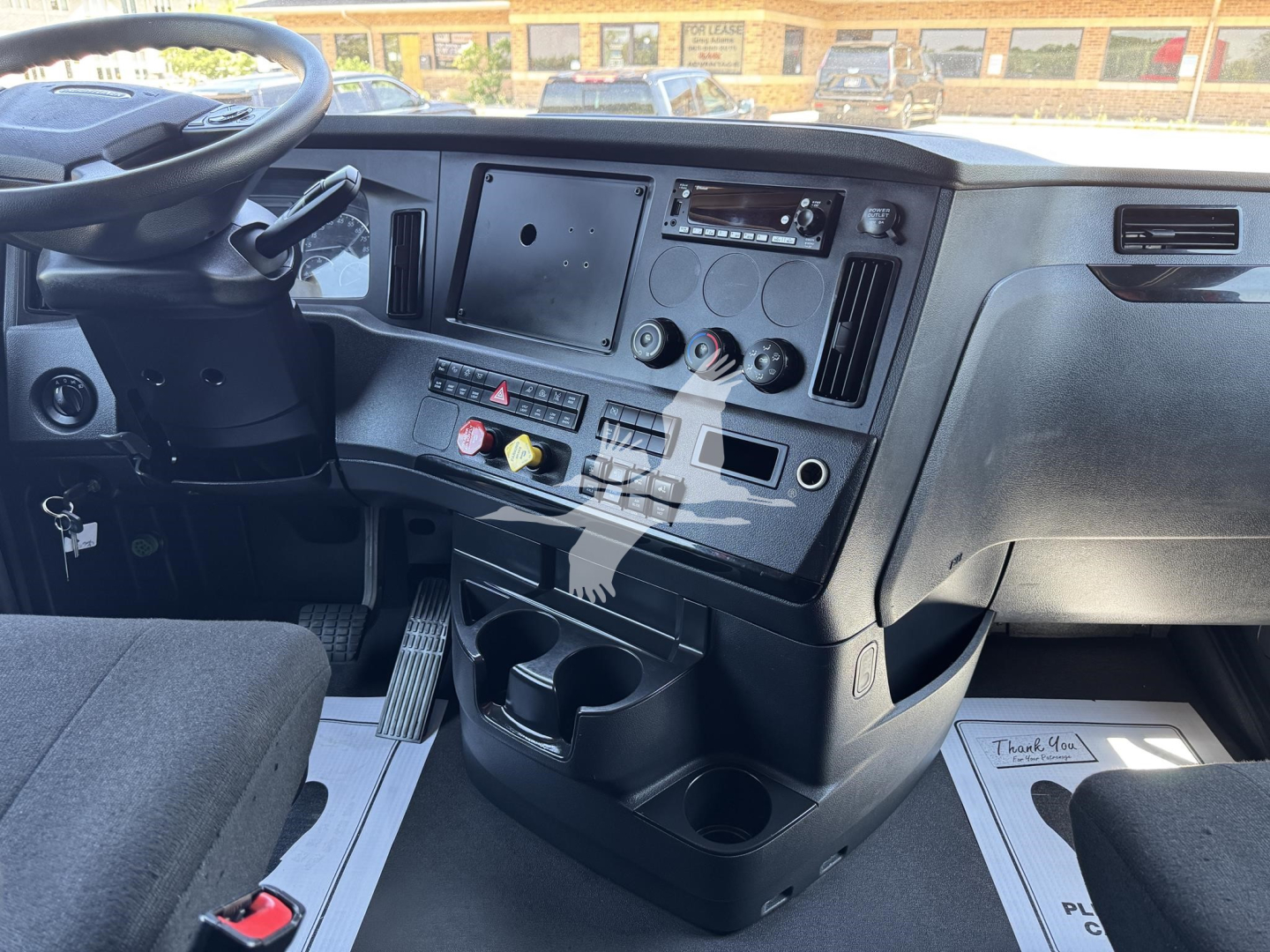 Cab interior of Freightliner Cascadia 126 showing dashboard with steering wheel, center control panel, cup holders, and seating in a sleeper truck.