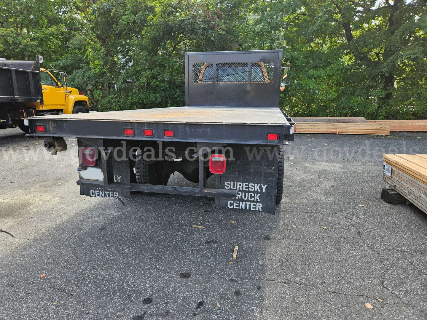 Flatbed dump truck rear view showing flatbed with taillights, rear mud flaps reading CENTER and SURESKY PUCK CENTER, VIN label on left, truck bed and surface details visible.