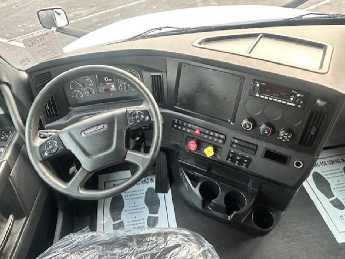 Truck cab interior of a 2023 Freightliner Cascadia 126 showing steering wheel, dashboard, and center console with various controls.