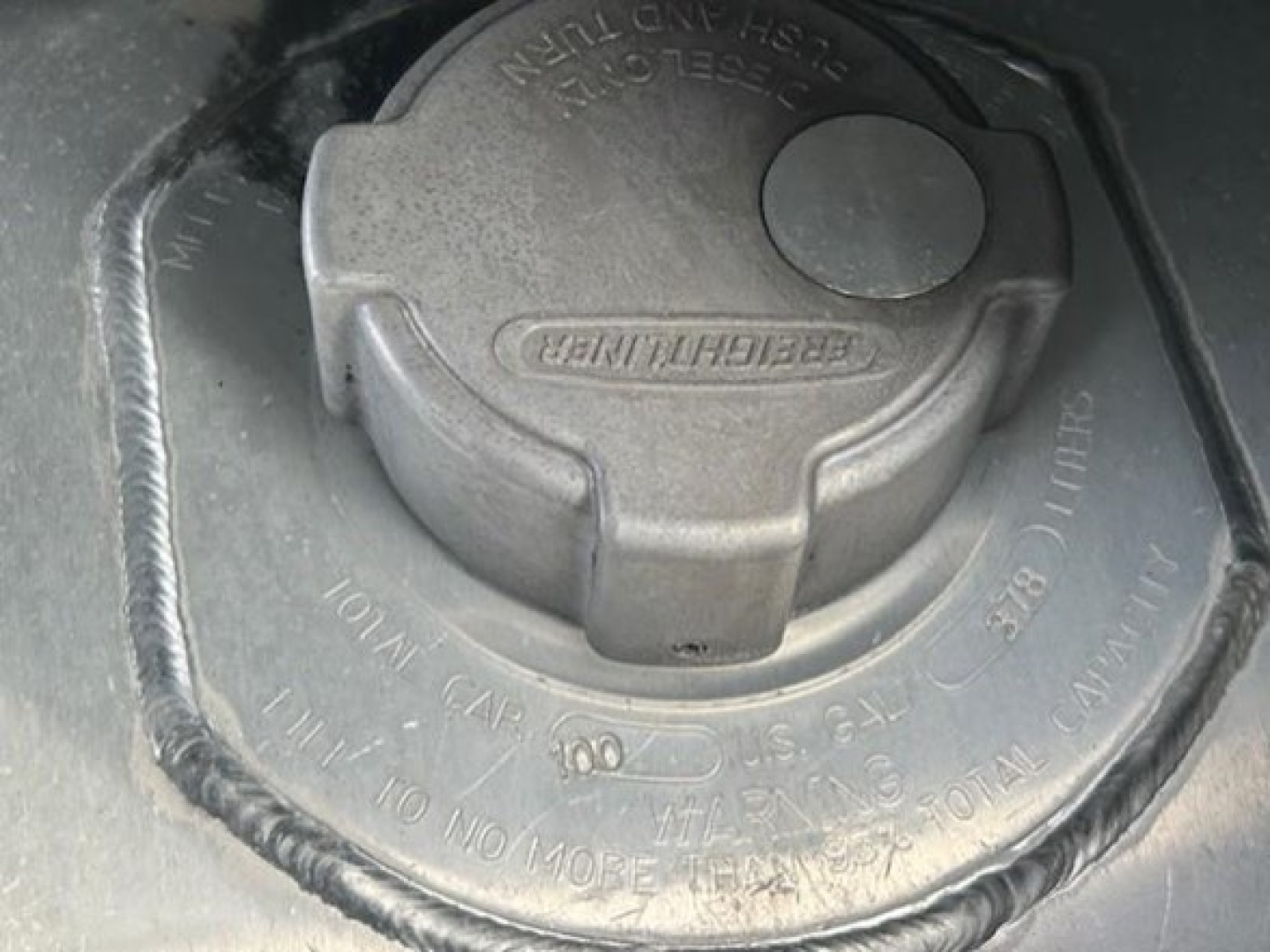 Fuel cap/diesel tank filler neck on Freightliner Cascadia fuel cap with locking ring and surrounding text.