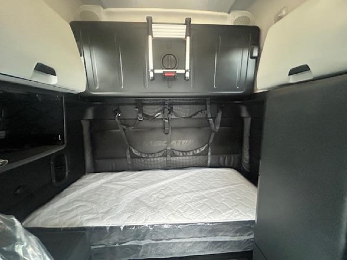 Freightliner Cascadia sleeper cab interior with bunk bed and storage compartments visible.