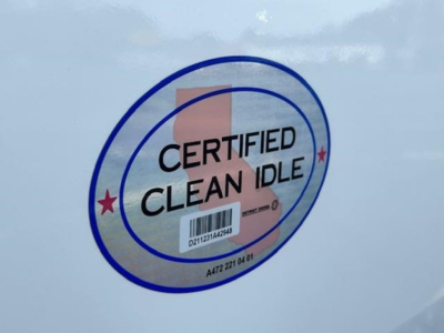Sticker reading Certified Clean Idle with barcode on a white Freightliner truck surface.