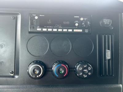 Truck instrument cluster panel with radio, climate controls, and vents in the cab of a Freightliner Cascadia 126 interior.