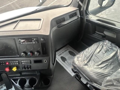 Cab interior of a Freightliner Cascadia 126 truck showing dashboard, steering column, and a plastic-covered driver seat.