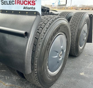 Freightliner Cascadia 126 rear tires and fender showing dual wheels and wheel covers with a SelecTrucks Atlanta sign in the background