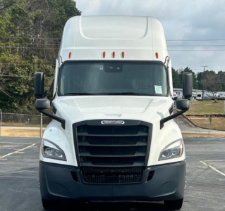 Front view of a white 2023 Freightliner Cascadia 126 sleeper cab truck in a parking lot.