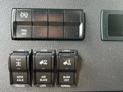 Truck dashboard switches and controls showing HSA OFF and various trailer/air suspension controls in a Cascadia cabin.