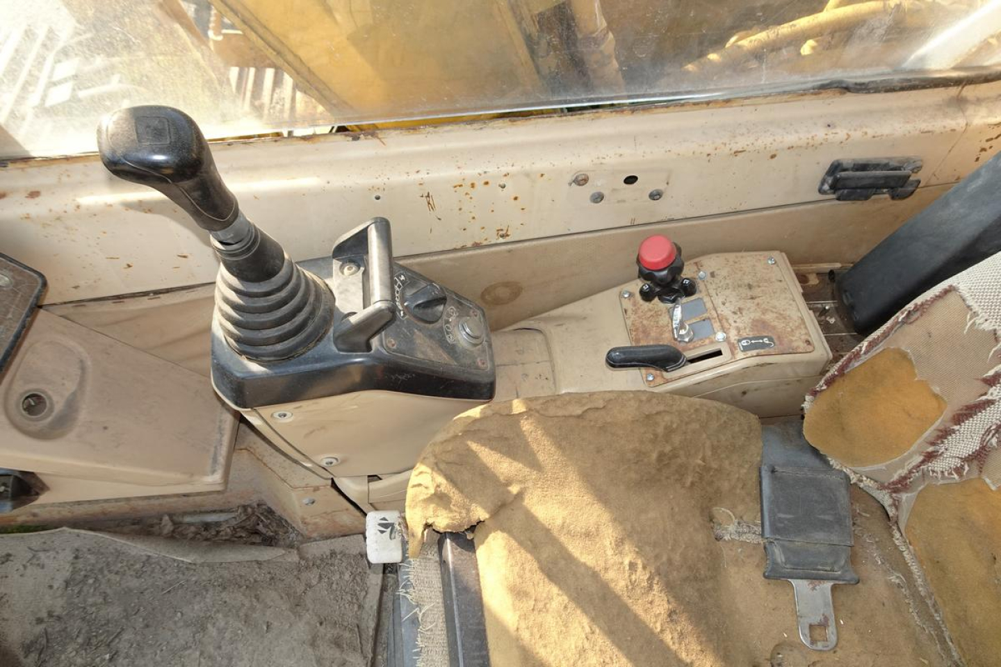 Caterpillar 312 excavator cab interior showing joystick control, gear selector, and dashboard with red push button.