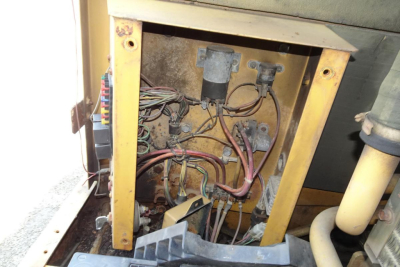 Electrical control panel inside a Caterpillar 312 excavator with exposed wiring and connectors.