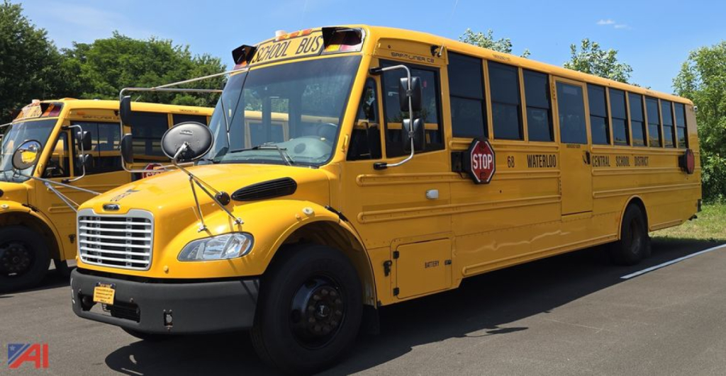 School bus showing front and side view with stop sign extended and 'SCHOOL BUS' signage on roof, yellow body, Freightliner Thomas C2 styling.
