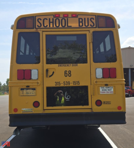 Back view of a yellow Freightliner Thomas B2 C2 school bus with 'SCHOOL BUS' sign, emergency door panel, number 68, and contact phone number visible.