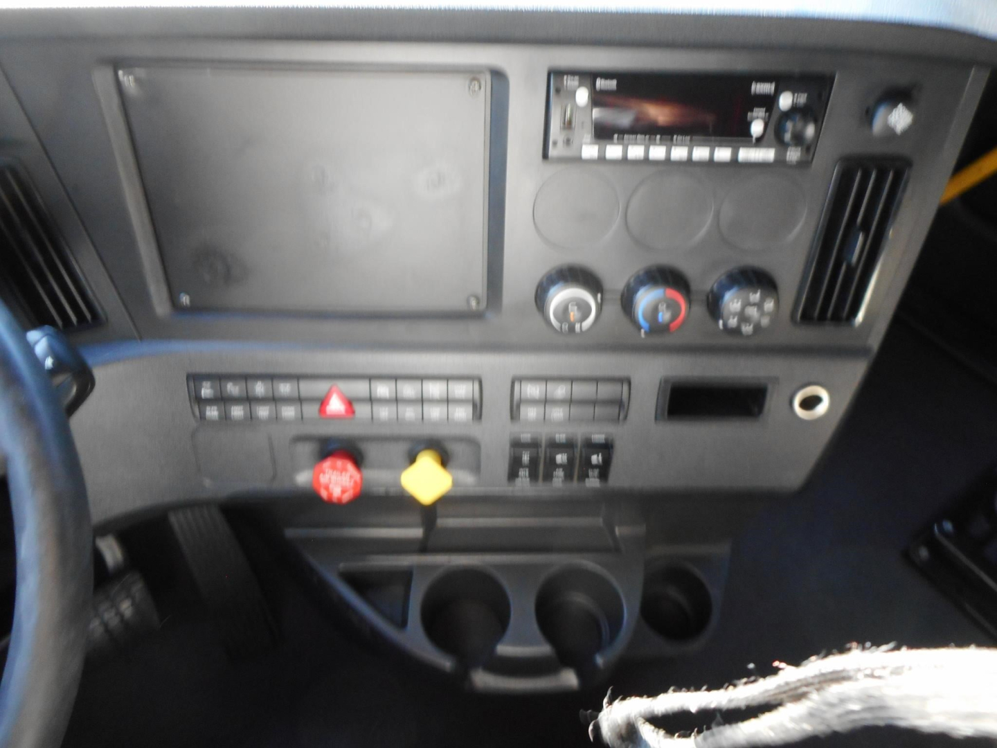 Dashboard of a 2024 Freightliner Cascadia 126 sleeper cab showing control panel with radio, climate controls, hazard switch, and cup holders.