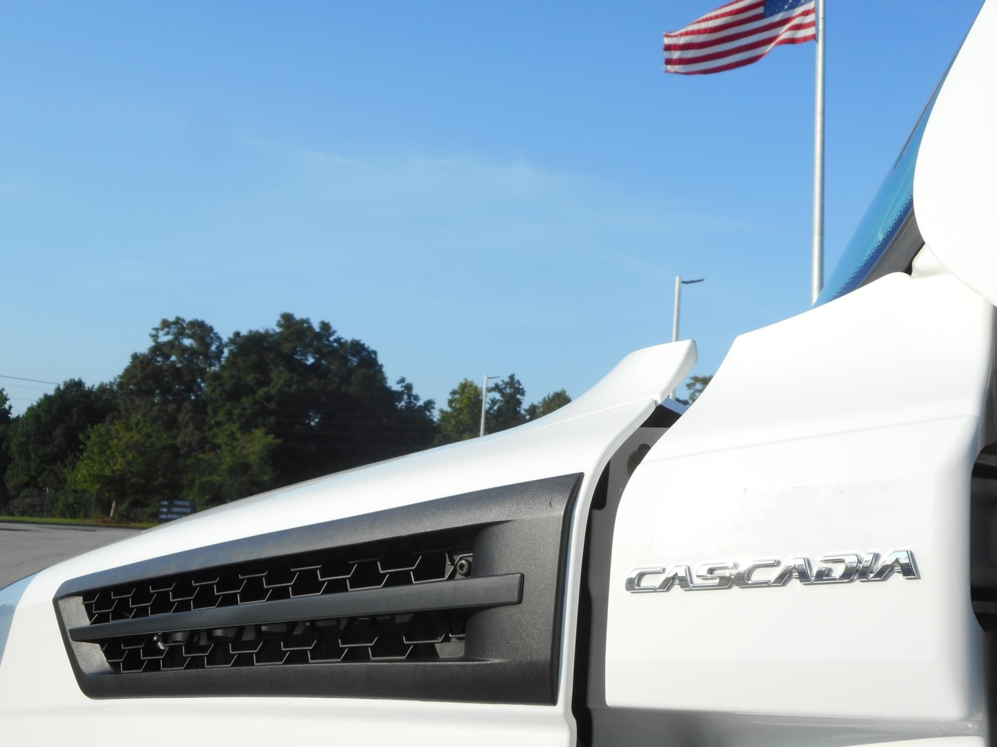 Front right section of a 2024 Freightliner Cascadia 126 truck showing the Cascadia badge on the cab and grille area.