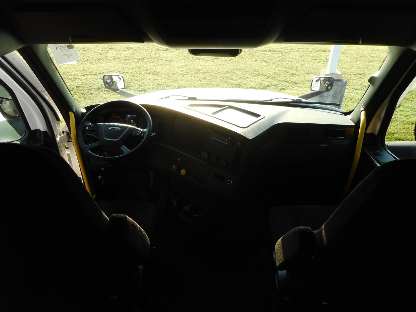 Dashboard view of Freightliner Cascadia truck interior with steering wheel, dash controls, and side mirrors visible through windshield.