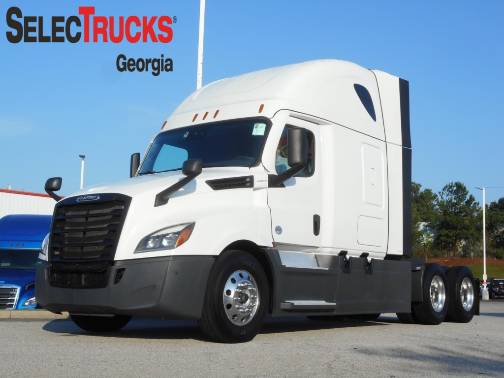 Freightliner Cascadia 126 sleeper tractor in a lot, white with black front bumper, three axles visible, SelecTrucks Georgia branding in top left.