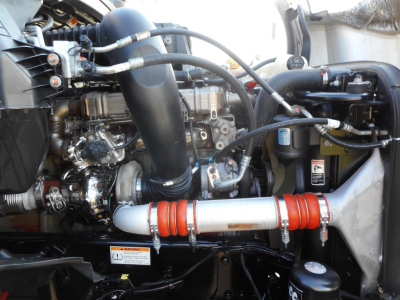 Freightliner Cascadia engine bay showing turbo hoses, intercooler piping, coolant reservoir, and brass-colored engine components.