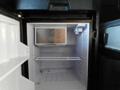Fridge compartment of a Freightliner Cascadia 126 cab showing empty freezer and shelves inside.