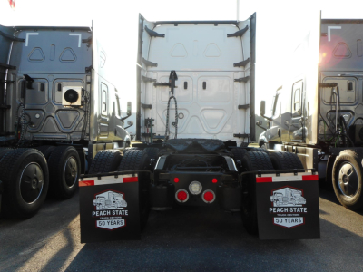 Rear view of a Freightliner Cascadia tractor with fifth wheel and mud flaps reading Peach State 50 Years; twin rear axles and clean white trailer backs.