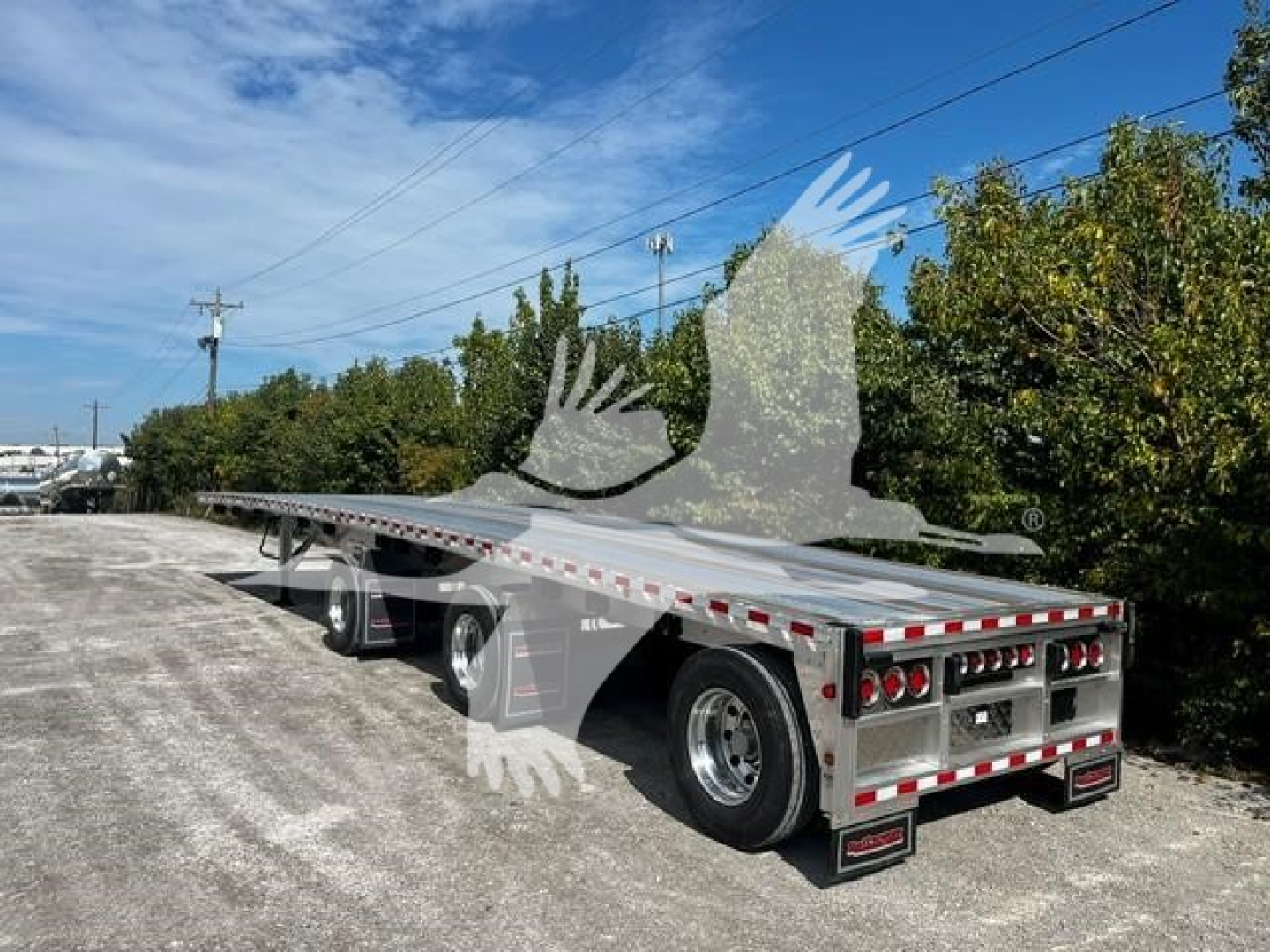 Flatbed trailer showing Tandem axle dual rear wheels and shiny metal deck with red/white reflective tape along edges. Rear ramp/console area visible. VIN 1RNF48A32VR081072 stock VR081072.