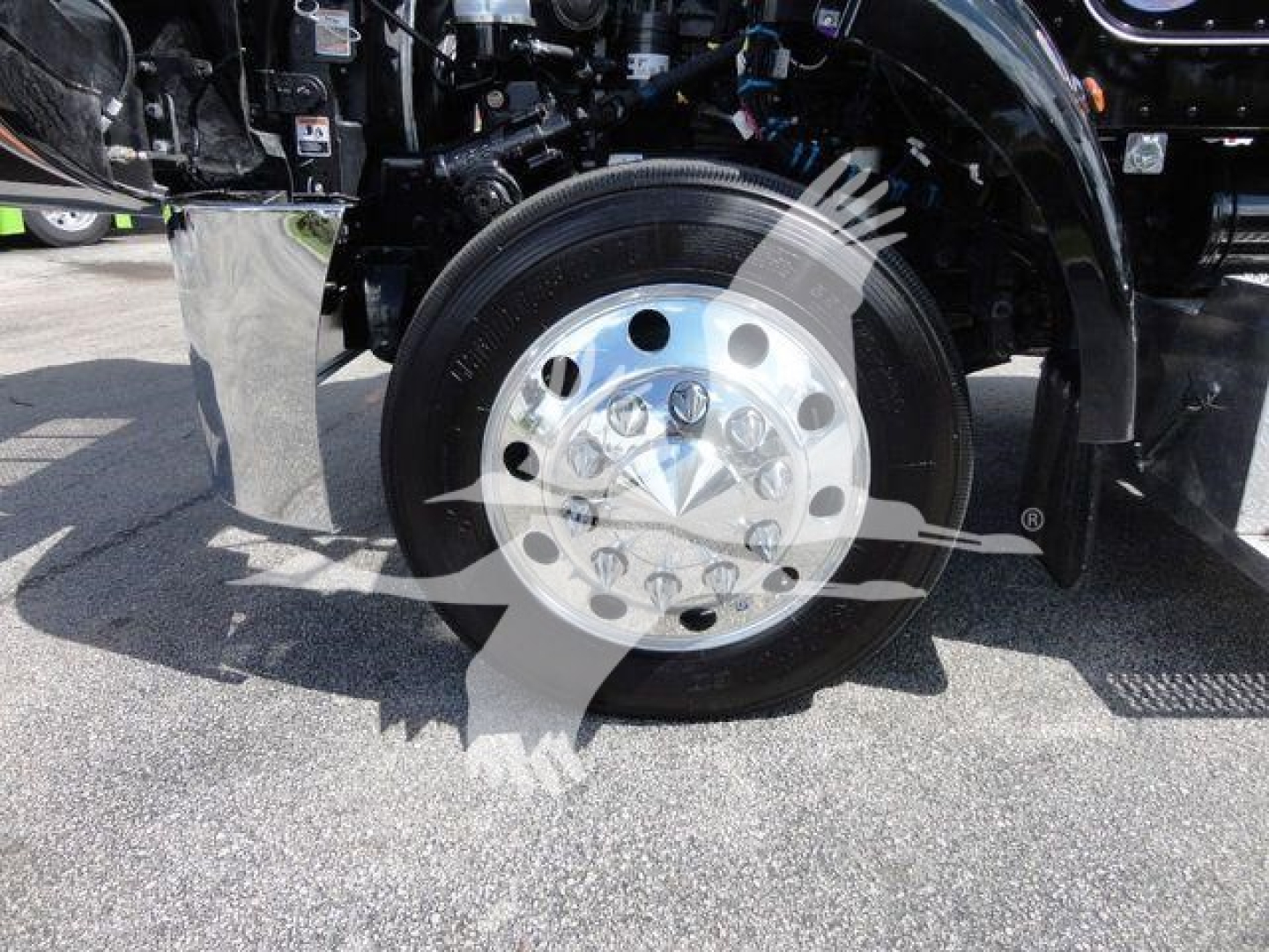 Peterbilt 337 truck front wheel chrome hubcap and tire view, front fender and suspension components visible