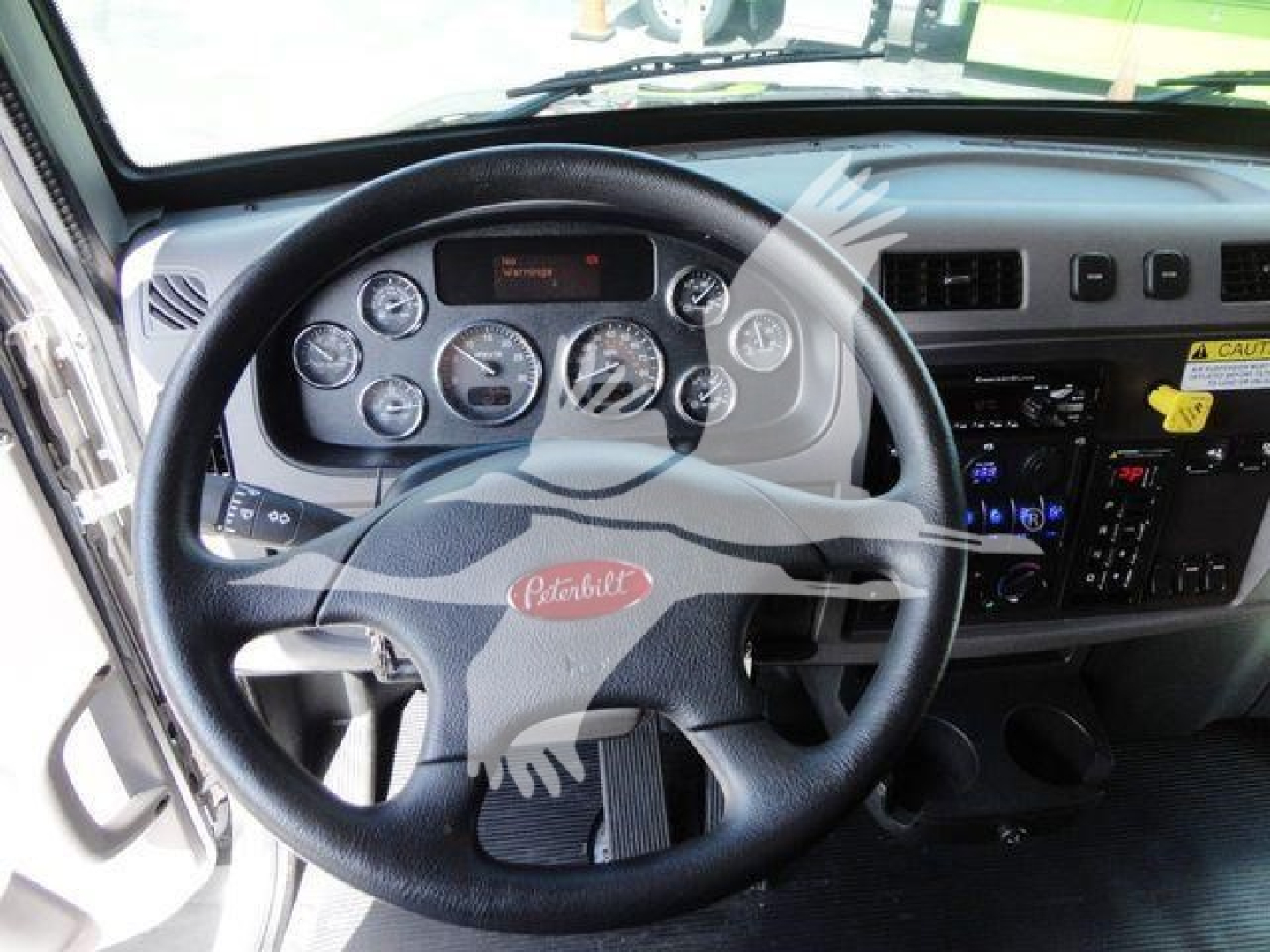 Peterbilt truck interior steering wheel and dashboard with gauges and controls visible.