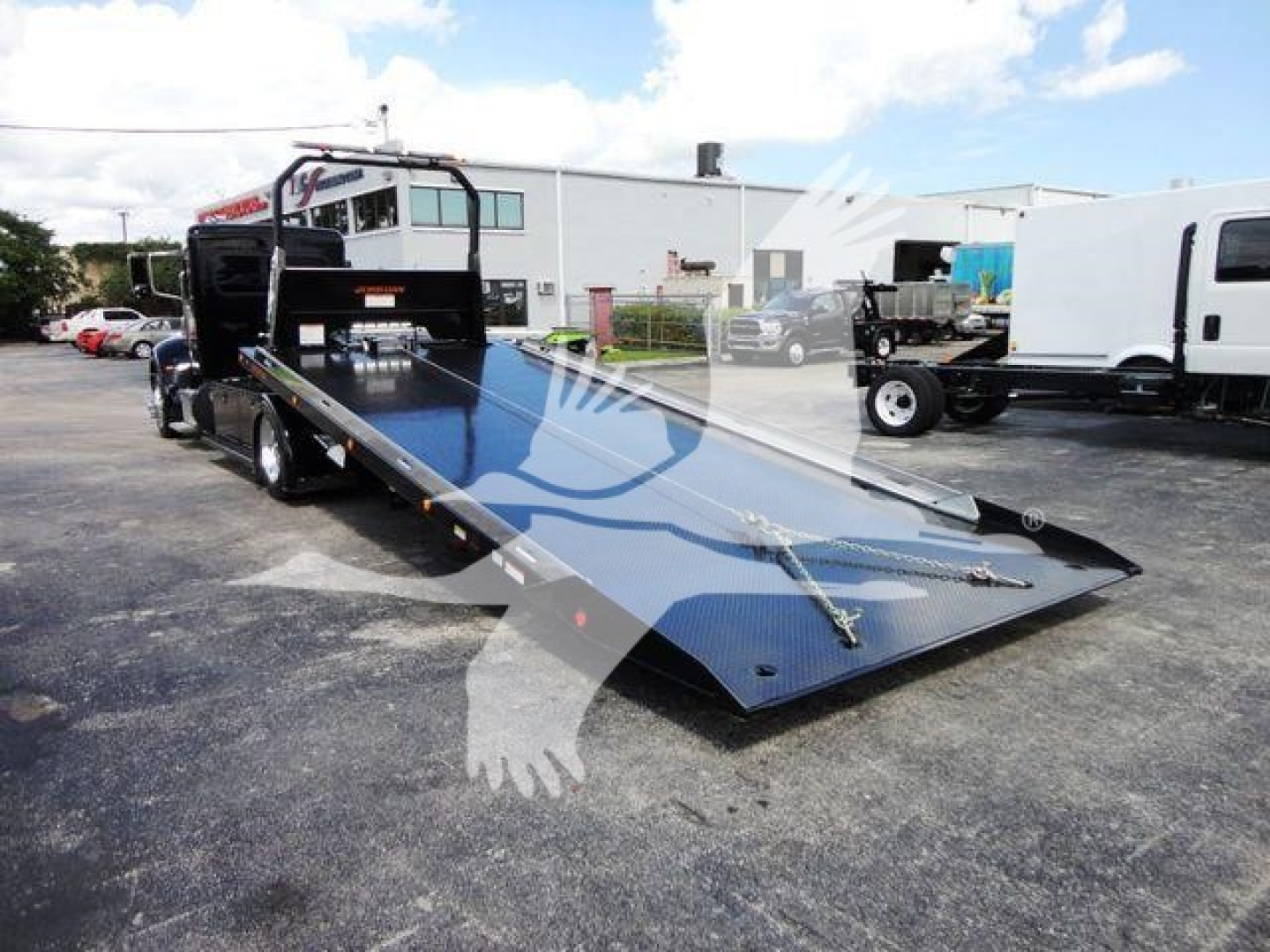 Peterbilt 337 rollback truck with a lowered flatbed ramp, showing a hydraulic tilt bed and wheel configuration.