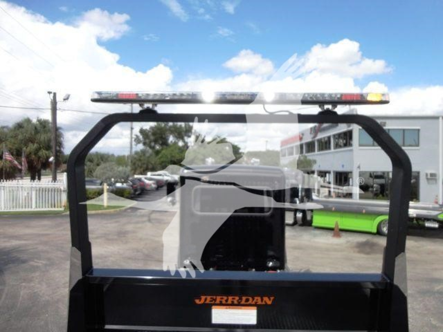 Peterbilt 337 rollback truck cab rear view with Jerr-Dan equipment mounting, light bar on top, and dealership building in background.