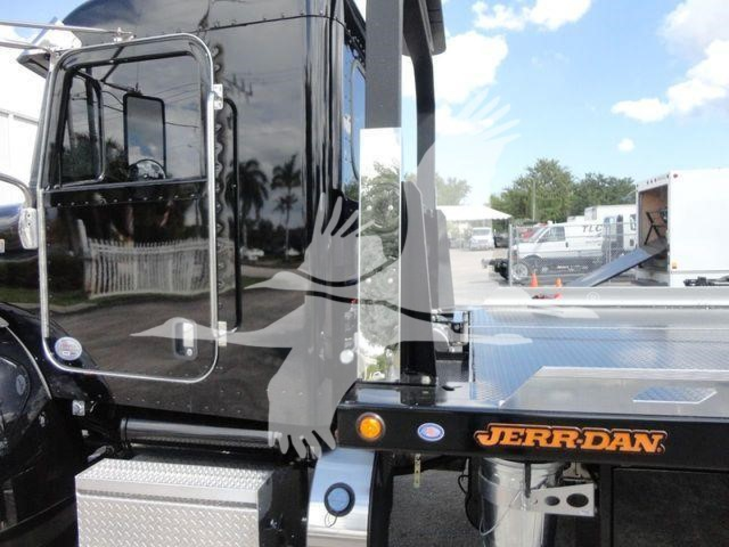 Peterbilt 337 rollback truck side view showing JERR-DAN equipment and cab door with reflective surface.