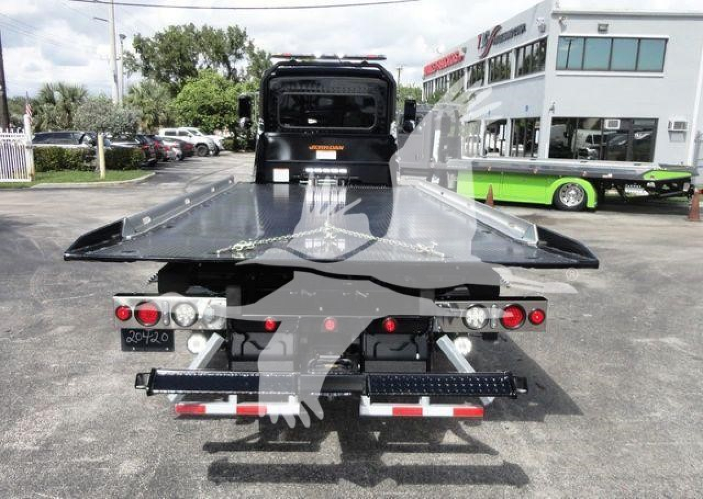 Peterbilt 337 rollback tow bed rear view showing flatbed with black steel deck, tail lights, and rear bumper with reflective strips.