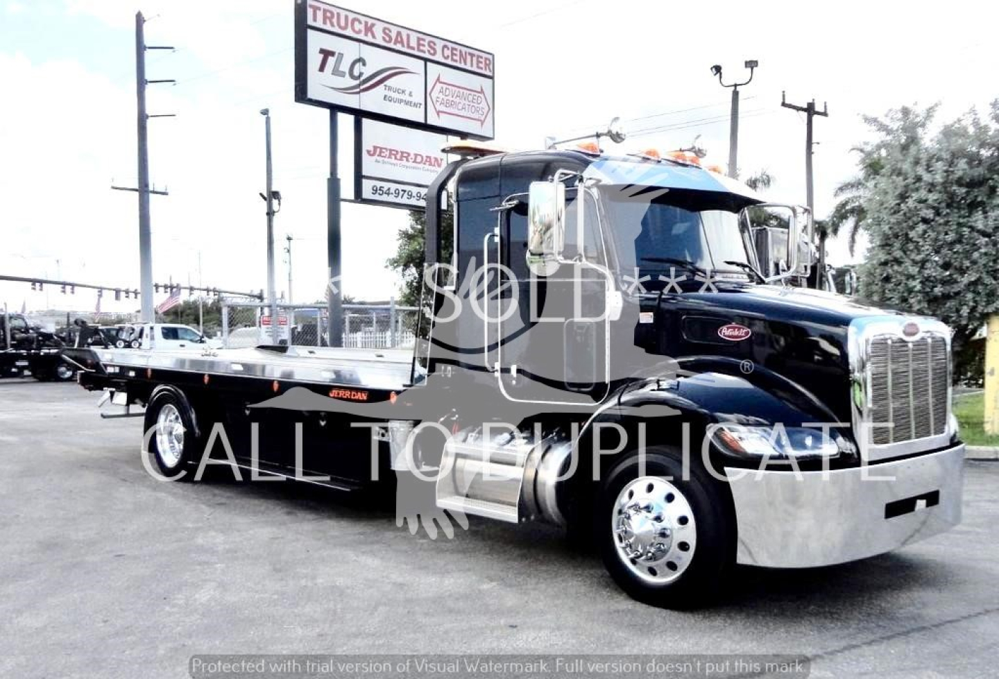 Peterbilt 337 rollback truck in view showing side profile and chrome bumper, black cab and long trailer with stock number J03058.