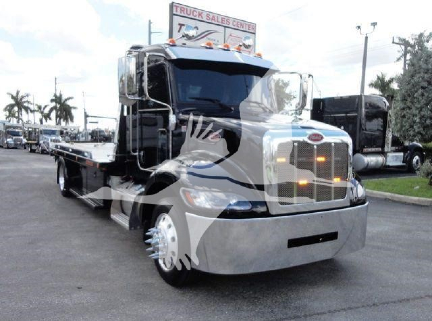 Peterbilt 337 rollback truck front view showing chrome bumper and grille with flatbed, daytime dealership lot