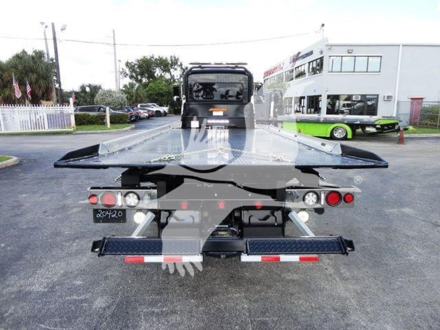 Peterbilt 337 rollback truck rear view showing flatbed and equipment, stock number J03058, dealership lot in background.