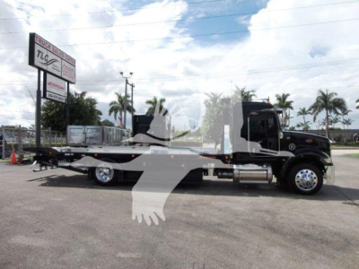 Truck side view of a 2022 Peterbilt 337 rollback tow truck showing long flatbed and cab with fuel tanks