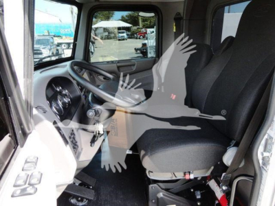 Interior of a 2022 Peterbilt 337 cab showing driver's seat and steering wheel with dashboard controls visible.