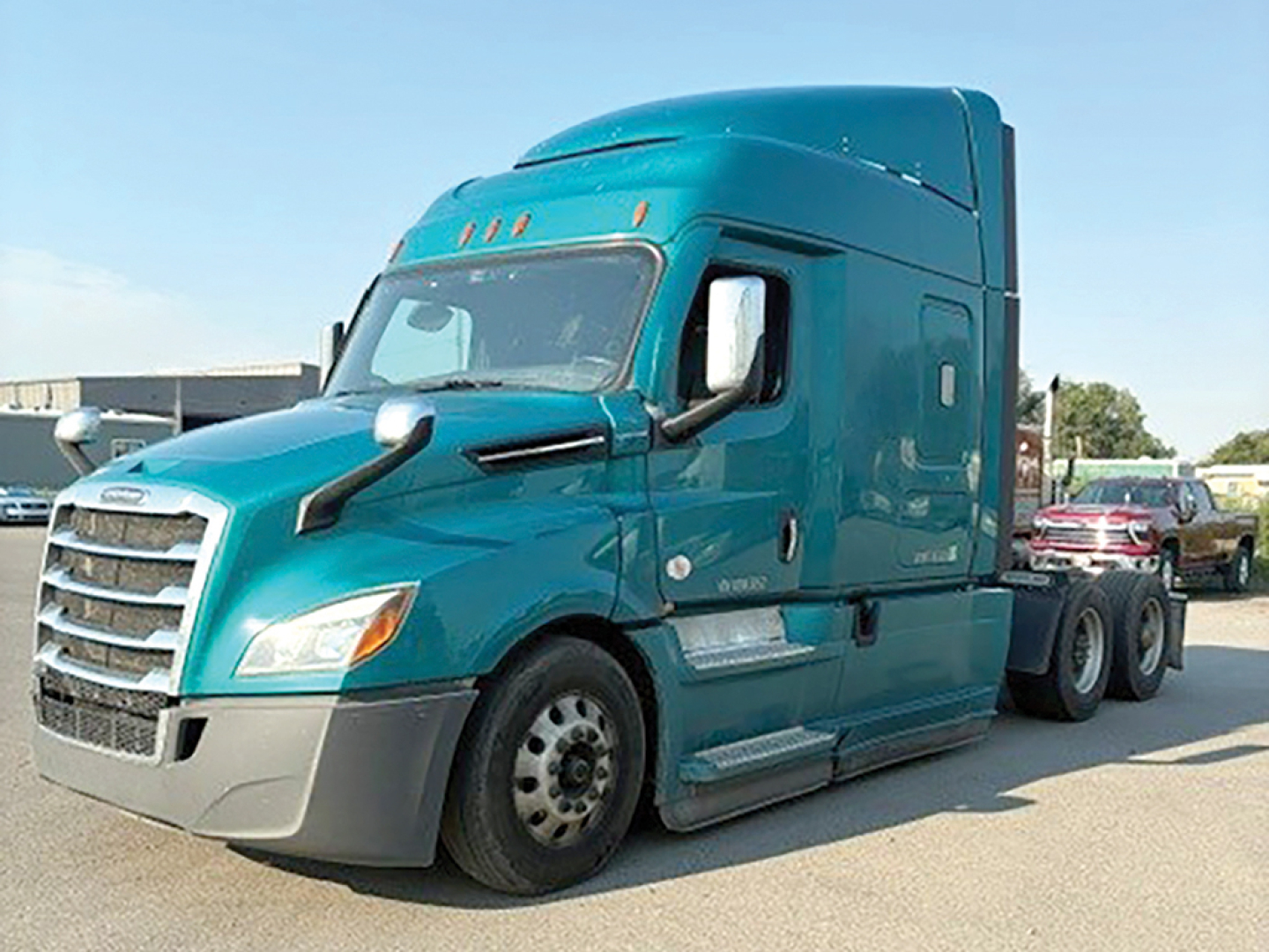 Cargo tractor cab in teal showing Freightliner Cascadia 126 with sleeper bay and dual rear axles, front grille, side mirrors, and step boards.