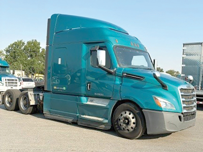 Truck front side view showing turquoise Freightliner Cascadia126 sleeper with aerodynamic hood and detached wheel at front, no visible text