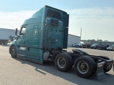 Truck tractor, teal Freightliner Cascadia 126, rear view showing fifth wheel and dual rear axles, side view mirrors, engine bay area, no cab interior visible.