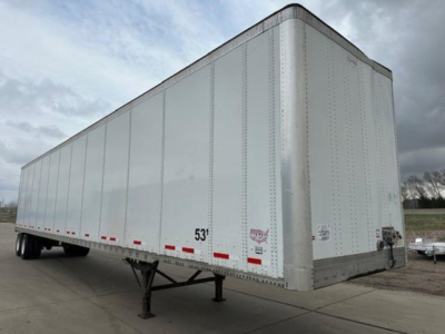 Trailer side and front showing a white Wabash van trailer with 53' length, loading legs lowered, DOT markings, and reflective tape along lower edge.